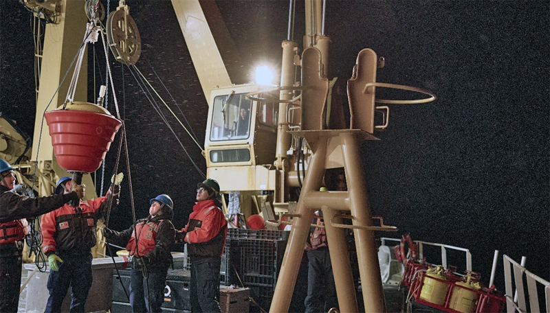 Crew on deck at night preparing to deploy buoy.