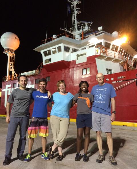 team in front of boat
