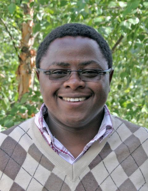 Amon Kimeli headshot with leafy trees in the background.