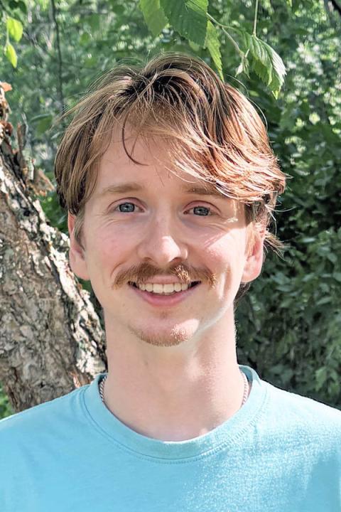 Headshot of Wylder Tonkin outside with tree leaves in the background.