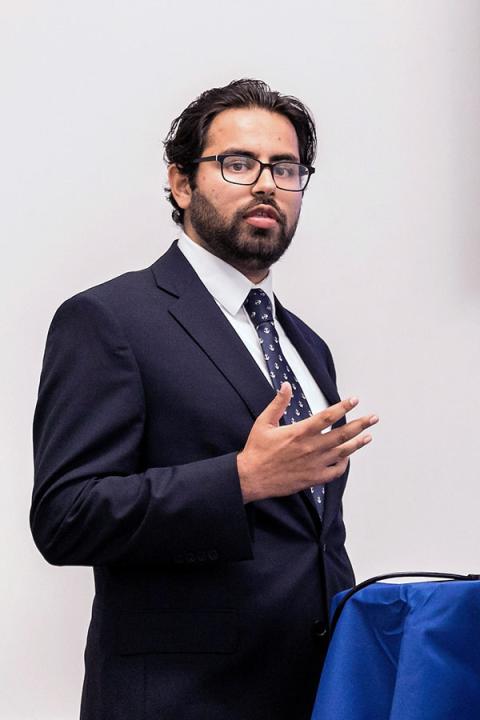Rohan Vaswani in dark suit gesturing with right hand.